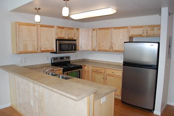 An empty kitchen with wooden cabinets and stainless steel appliances